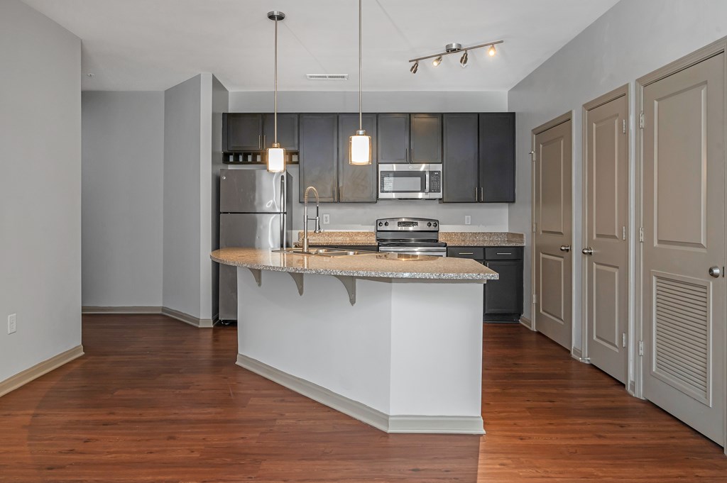 A kitchen with a white island and wooden floors.